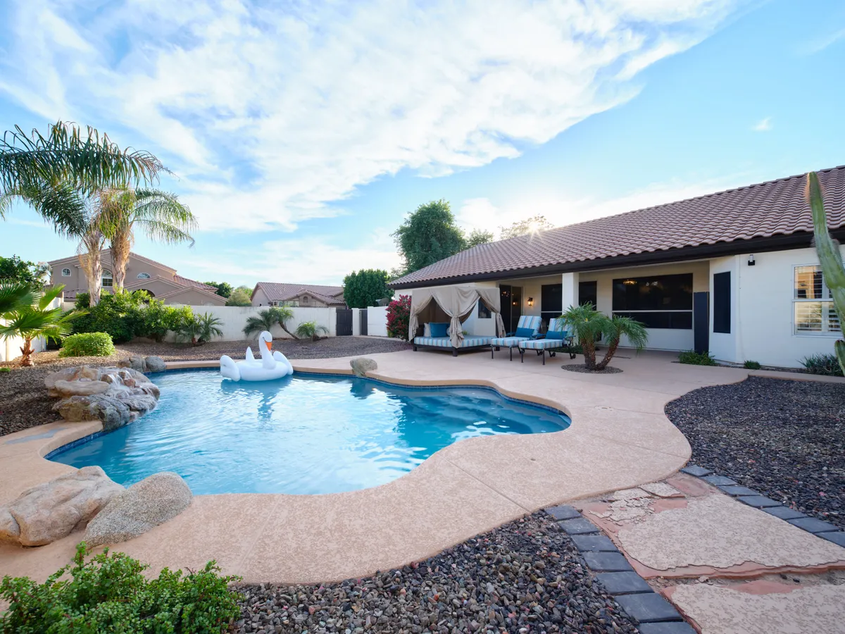 A cheerful view of the swimming pool featuring a swan float, outdoor seating area, and greenery. The scene evokes playfulness and leisure, suggesting family fun and opportunities for both relaxation and pool parties.