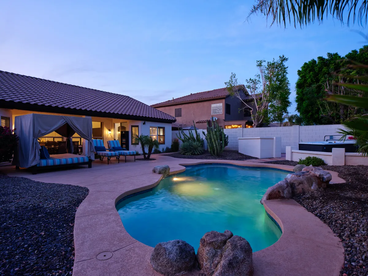 A stylish outdoor oasis with a swimming pool, lounge chairs, canopy, and lush landscaping. The tranquil setting suggests relaxation, entertaining, and continued fun at home, especially after a night out.